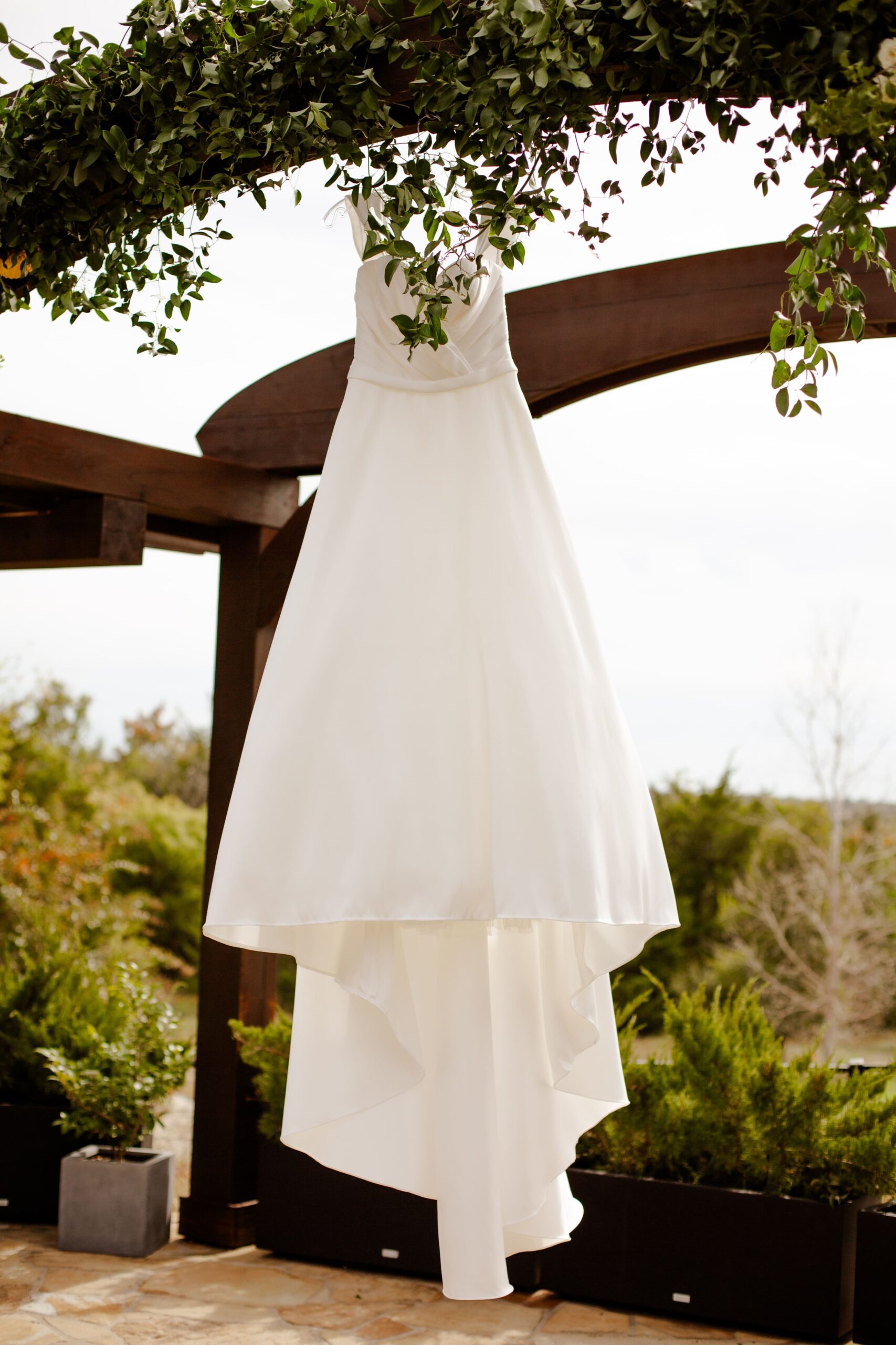 Wedding dress hanging at outdoor ceremony with winter florals in Texas